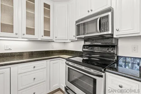 a kitchen with granite countertop white cabinets and stainless steel appliances