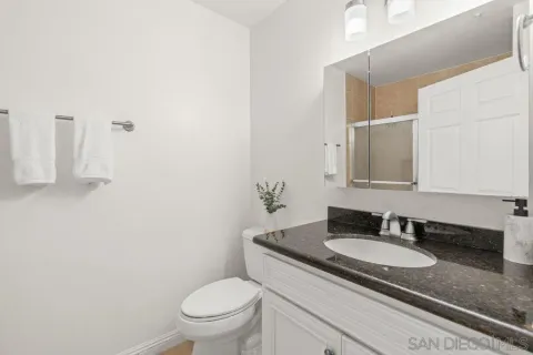a bathroom with a granite countertop sink a toilet and a mirror