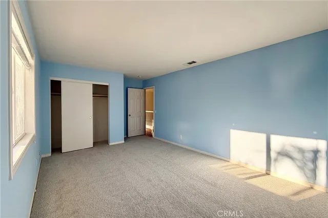 an empty room with closet and windows