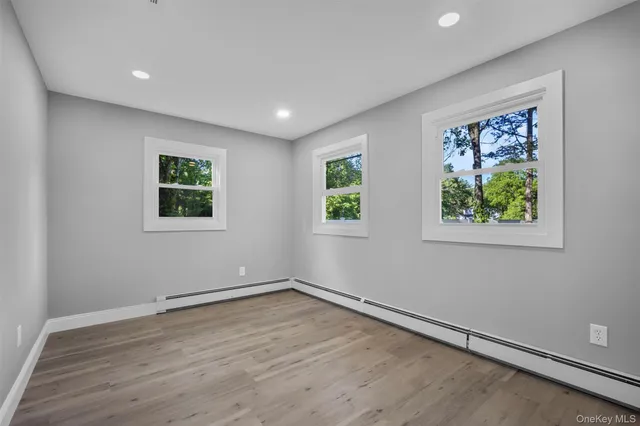 a view of empty room with wooden floor and window
