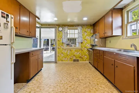a large kitchen with stainless steel appliances kitchen island granite countertop a refrigerator and a sink