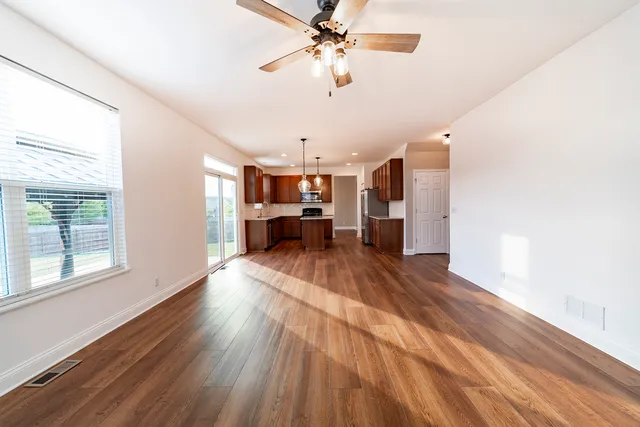 a view of a living room with kitchen furniture and a ceiling fan