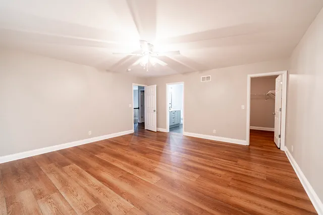 an empty room with wooden floor and a ceiling fan