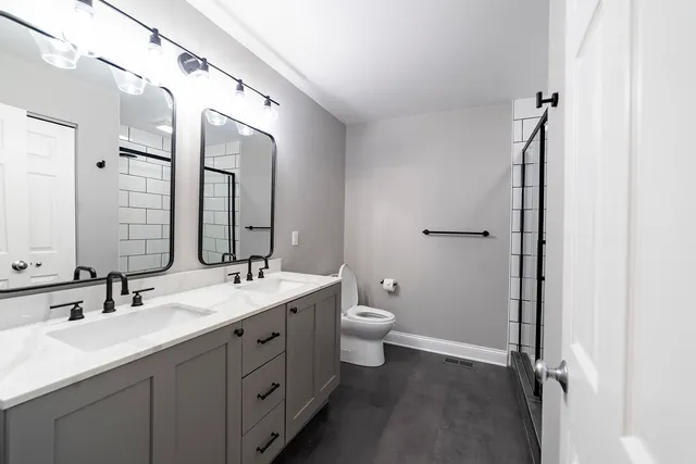 a bathroom with a double vanity sink toilet and mirror