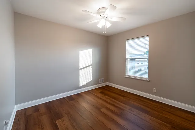 a view of an empty room with chandelier fan and a window