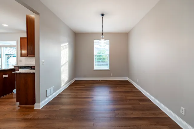 a view of an empty room with window and wooden floor