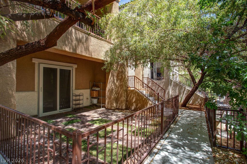 7724 Vibrant Thread Court Las Vegas, NV 89149 - Photo 40 of 43 A private outdoor space with a paved patio area, framed by lush foliage and elegant railings.