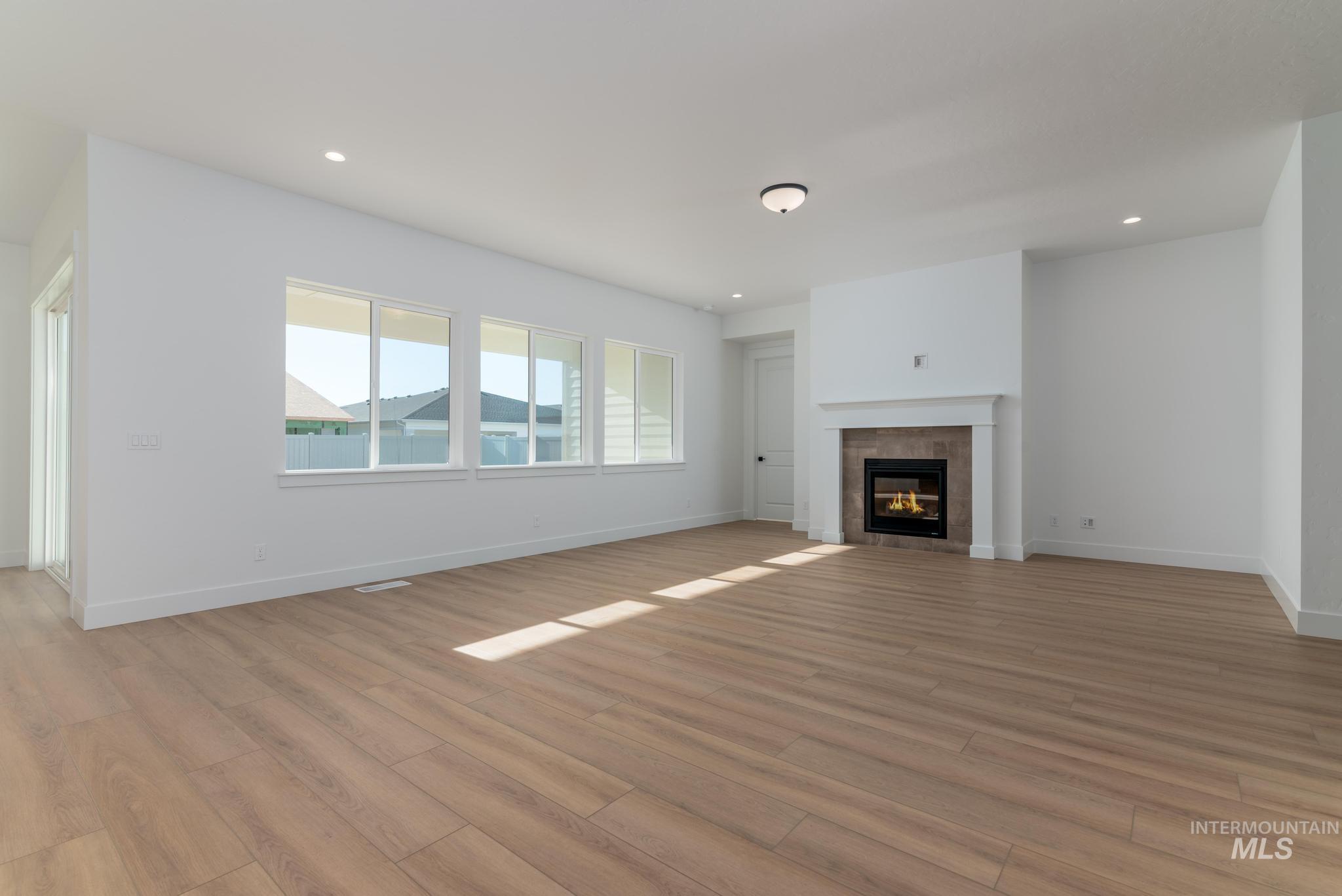 9085 West Patmore Court Star, ID 83669 - Photo 5 of 40 Unfurnished living room with a fireplace, light wood-style flooring, and recessed lighting