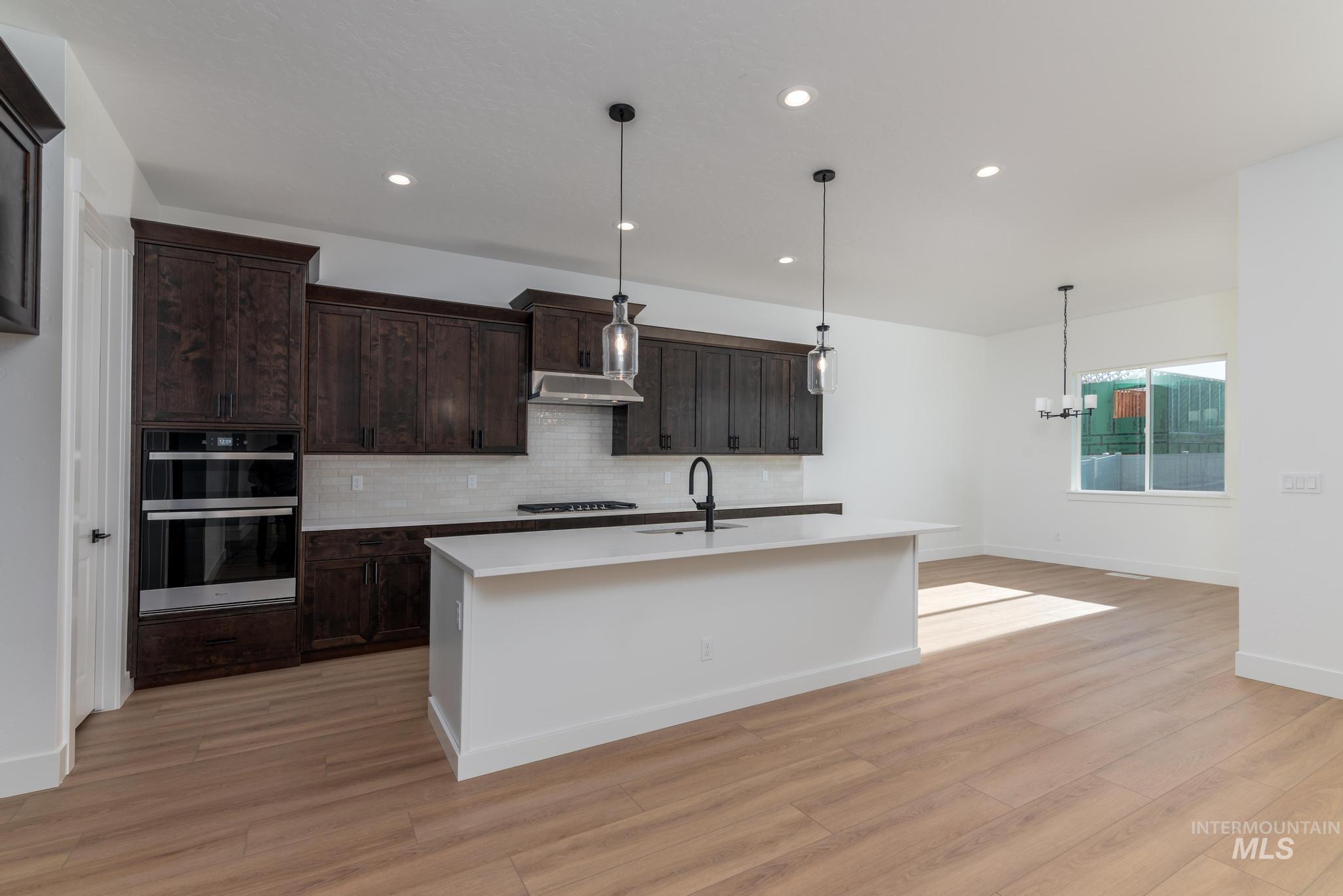 9085 West Patmore Court Star, ID 83669 - Photo 9 of 40 Kitchen featuring pendant lighting, decorative backsplash, stainless steel double oven, a center island with sink, and recessed lighting