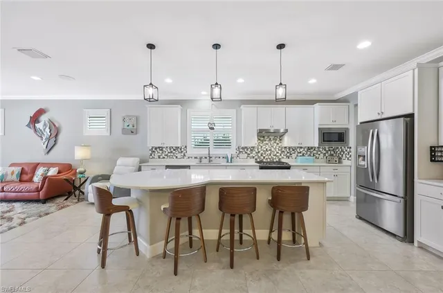 a kitchen with stainless steel appliances granite countertop a sink a stove a refrigerator and island with wooden floor