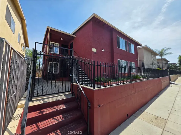 a view of a brick house with iron fence