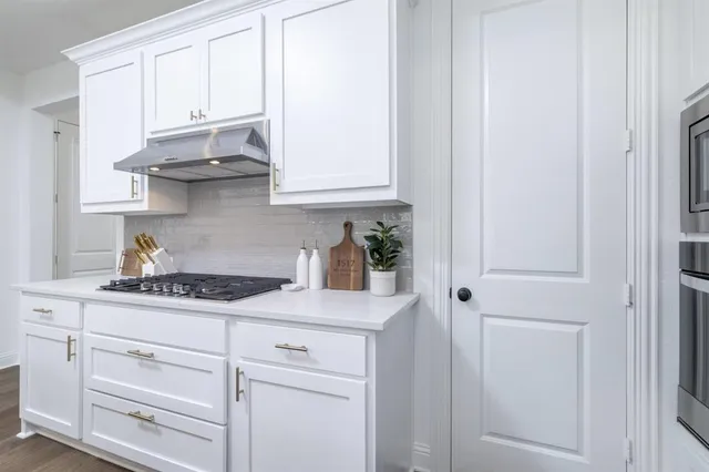 a kitchen with white cabinets and a window
