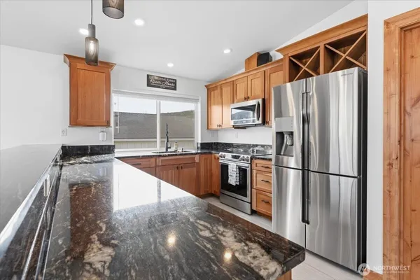 a kitchen with stainless steel appliances granite countertop a refrigerator a stove and a sink with wooden floor
