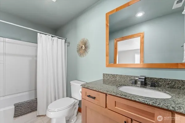 a bathroom with a granite countertop sink a toilet and a mirror