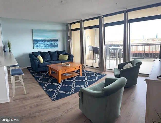 a living room with furniture floor to ceiling windows and wooden floor