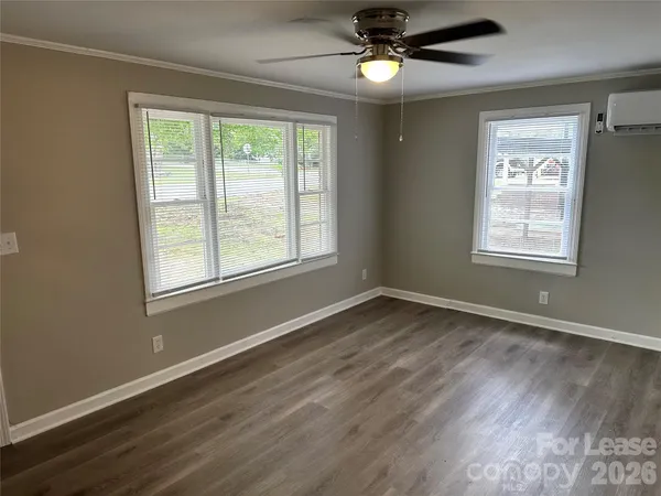 a view of an empty room with a window and wooden floor