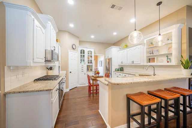 a kitchen with stainless steel appliances granite countertop table chairs sink and stove top oven