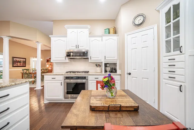 a kitchen with stainless steel appliances granite countertop a stove and white cabinets