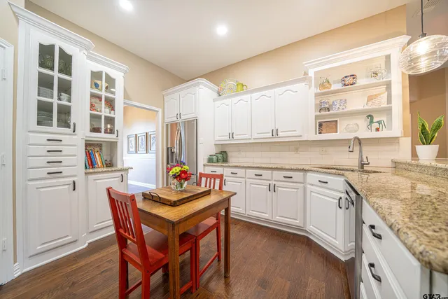 a kitchen with stainless steel appliances granite countertop a stove and white cabinets next to a window