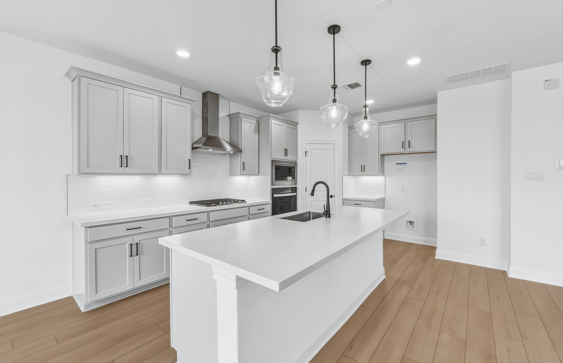 421 Foresail Road Leander, TX 78641 - Photo 26 of 28 a large white kitchen with stainless steel appliances granite countertop a stove a sink a refrigerator and white cabinets with wooden floor