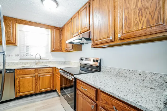 a kitchen with stainless steel appliances granite countertop a sink dishwasher stove and cabinets with wooden floor