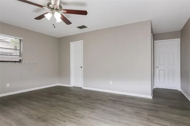 an empty room with wooden floor chandelier fan and closet area