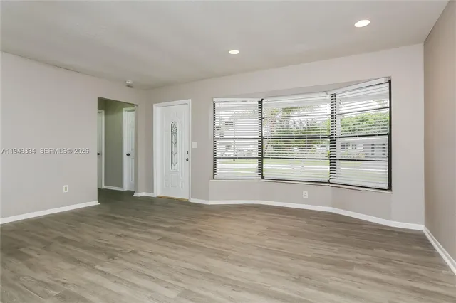 a view of an empty room with wooden floor and a window
