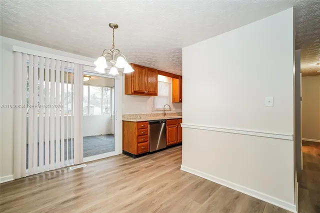 a kitchen with stainless steel appliances granite countertop a refrigerator a sink dishwasher a stove a dining table and chairs