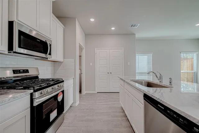 a kitchen with granite countertop stainless steel appliances a sink a stove and cabinets
