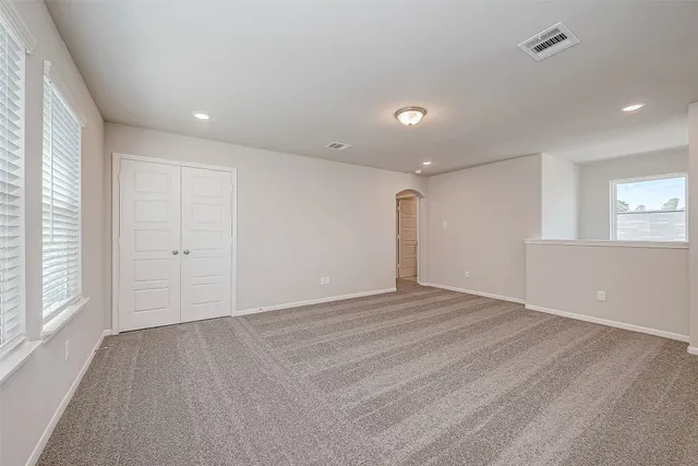 a view of an empty room with wooden floor and windows
