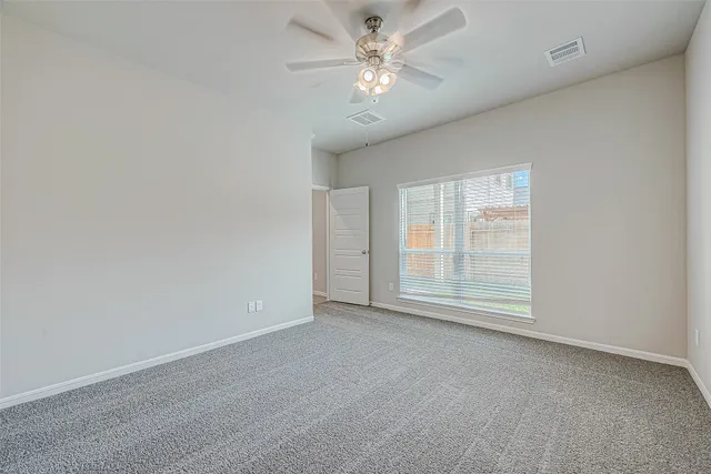 an empty room with a chandelier fan and windows
