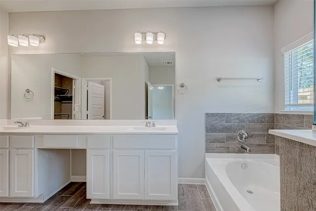 a spacious bathroom with a tub sink and mirror