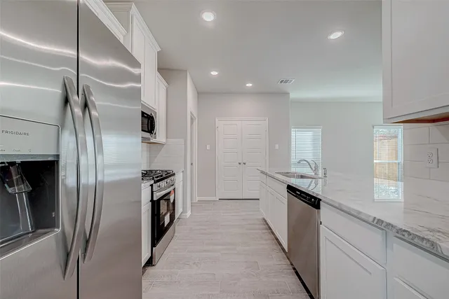 a kitchen with stainless steel appliances granite countertop a refrigerator and a sink
