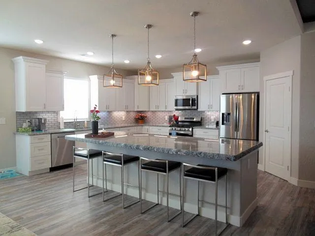 a kitchen with stainless steel appliances granite countertop a sink a stove a refrigerator cabinets and wooden floor