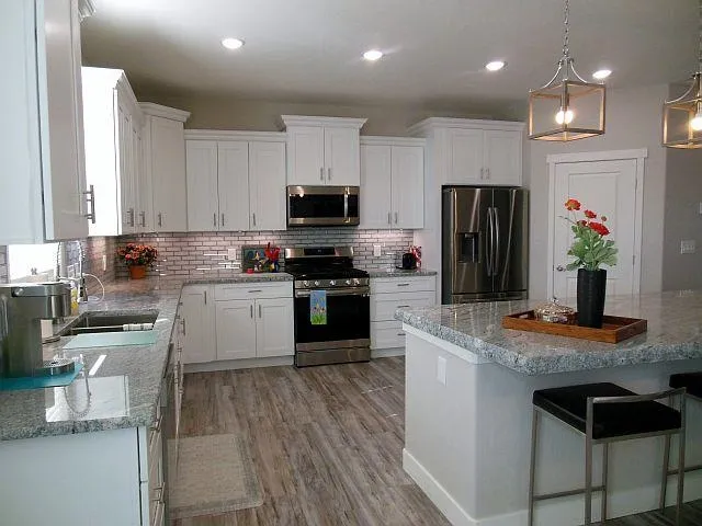 a kitchen with kitchen island granite countertop stainless steel appliances cabinets a sink and a counter top space