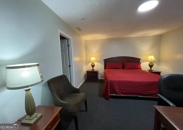 a bedroom with a bed a lamp on desk and a chair
