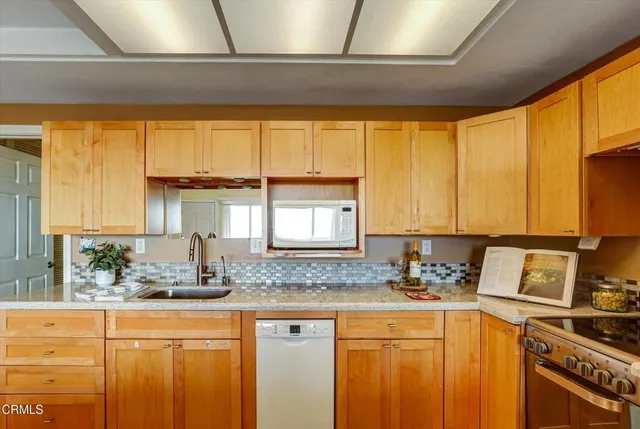 a kitchen with stainless steel appliances a sink a stove and white cabinets next to a window
