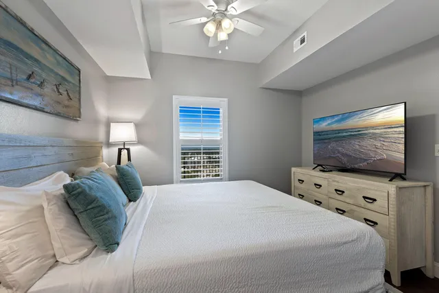a bedroom with a flat screen tv on the dresser and a chandelier