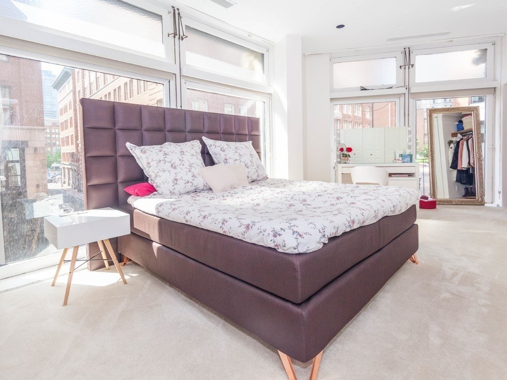 86 South Street, Unit 2A Boston, MA 02111 - Photo 18 of 24 a bed sitting in a bedroom next to a window with a lamp and a table