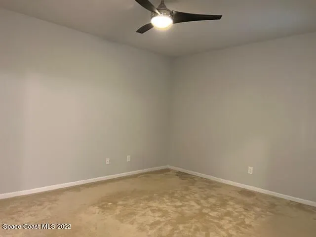 an empty room with a ceiling fan and carpet