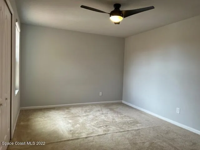 an empty room with a ceiling fan and window