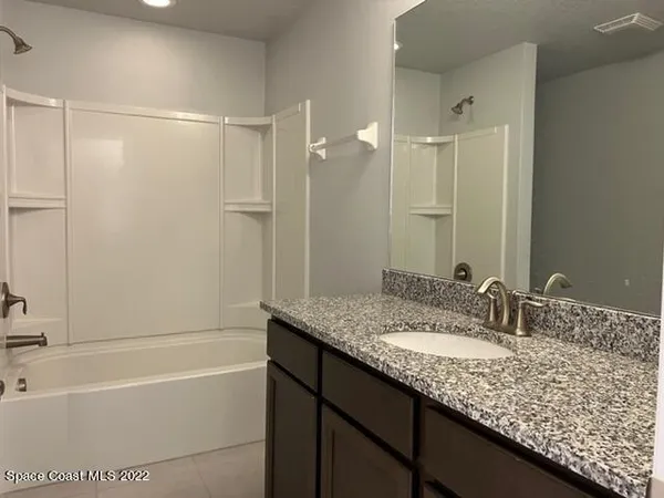 a bathroom with a granite countertop sink mirror and a bath tub