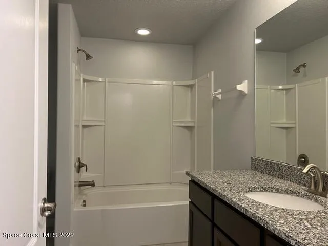 a bathroom with a granite countertop sink a mirror and a bathtub