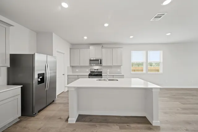 a kitchen with stainless steel appliances kitchen island a refrigerator sink and cabinets