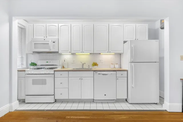 a kitchen with granite countertop white cabinets and refrigerator