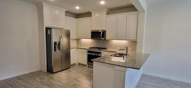 a kitchen with stainless steel appliances granite countertop a refrigerator and a stove