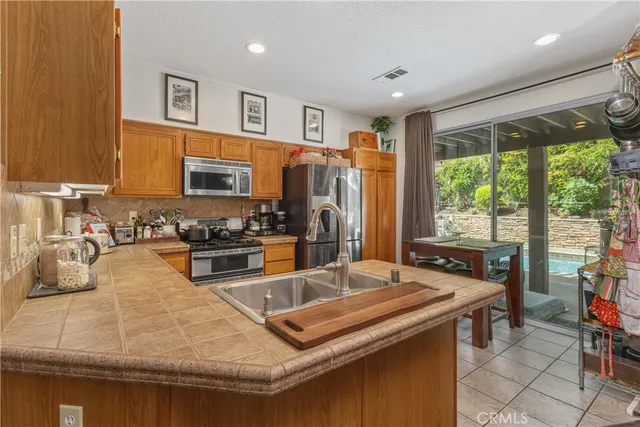 a kitchen with a stove a sink a refrigerator and chairs