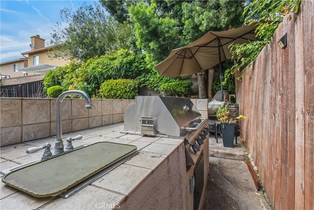 a backyard of a house with table and chairs under an umbrella