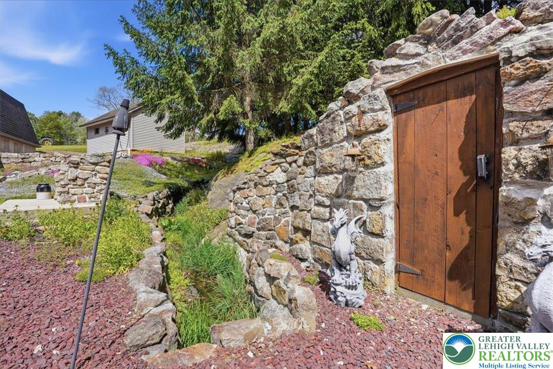 4880 Little Gap Road Kunkletown, PA 18058 - Photo 61 of 100 This charming outdoor setting features a rustic stone wall and a wooden door, complementing the natural landscape.