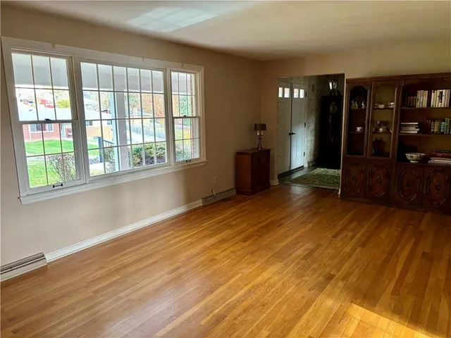 a view of an empty room with window and wooden floor